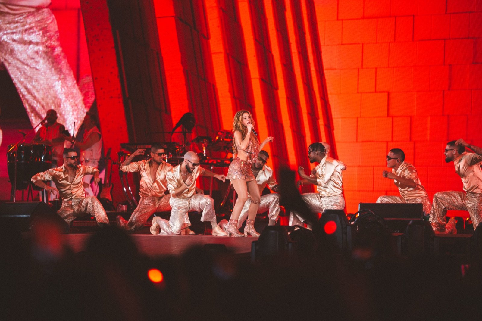Shakira y su cuerpo de baile ante el fondo rojo
