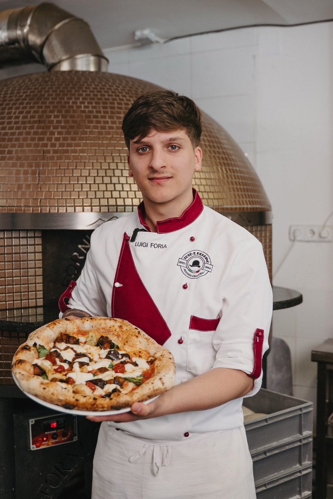 Pizzero sosteniendo una pizza recién hecha